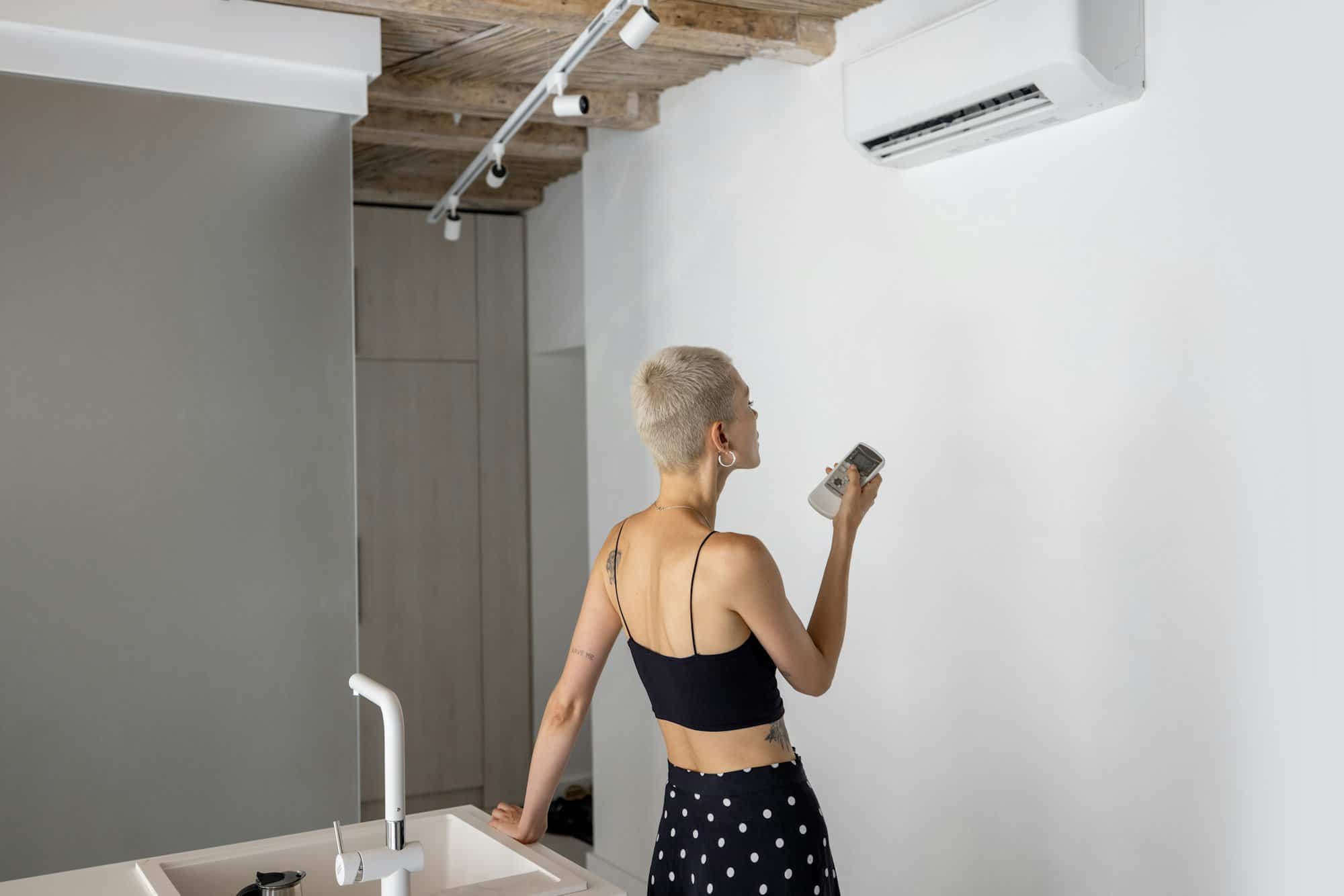 Woman sets the temperature on the air conditioner at home